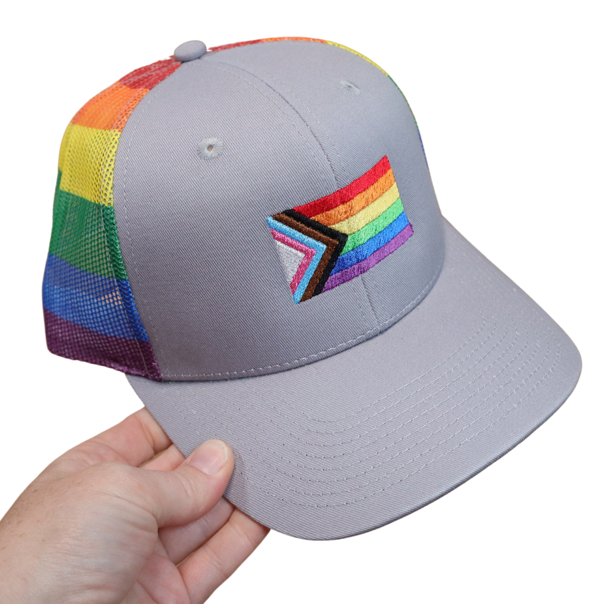 Gray structured snapback hat with the Progress Pride flag machine embroidered on the front and a rainbow striped mesh back, held in hand
