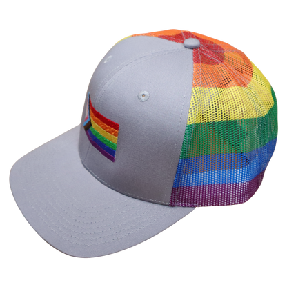 Side angle of a gray hat with Progress Pride flag embroidery on the front and rainbow striped mesh panels wrapping the back