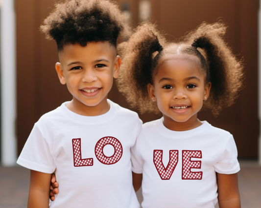 Two children posing in white short sleeve shirts with a red gingham applique, one shirt with LO and the other with VE. Together they spell "LOVE"
